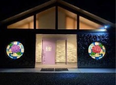 神宮寺あじさいトイレの夜景写真。丸窓にアジサイのモザイクガラスがはめ込まれている。